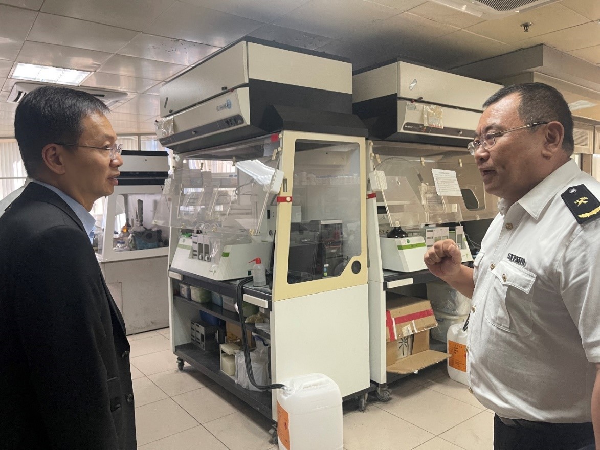 Dr. ZHENG Jianguo (right) presents an overview of the daily operations in the Food and Cosmetics Testing Institute.