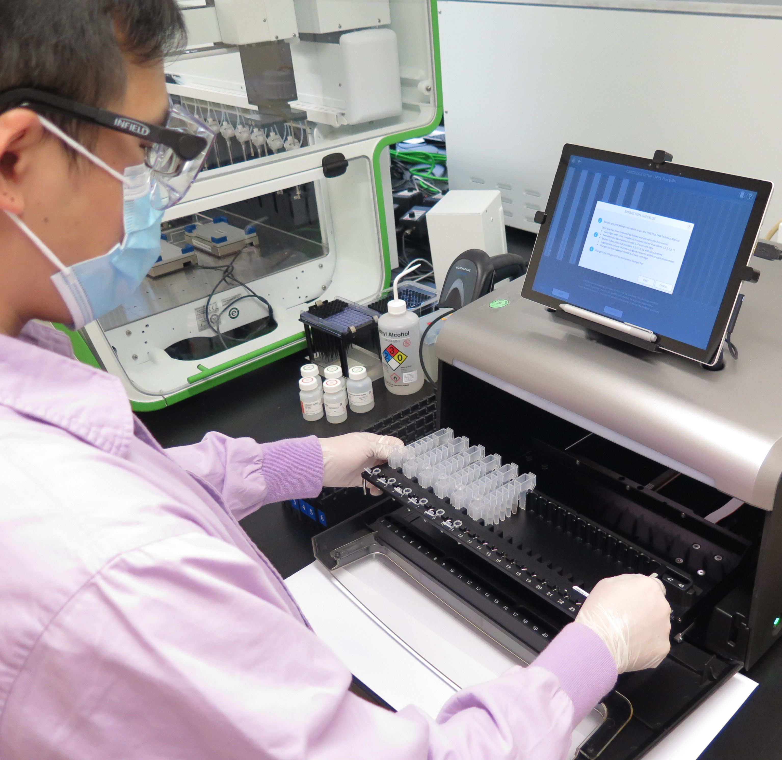 A staff is operating an automatic liquid handling system for DNA extraction